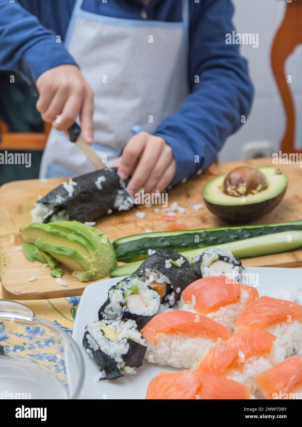 Bambino che prepara sushi fatto in casa. Attività in cucina adatte ai bambini Foto Stock