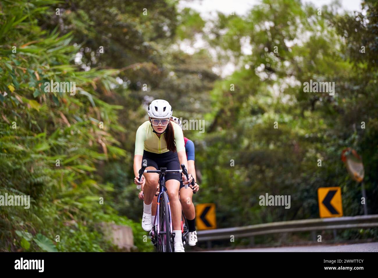 gruppo di giovani ciclisti professionisti asiatici che si allenano in bicicletta su strada rurale Foto Stock