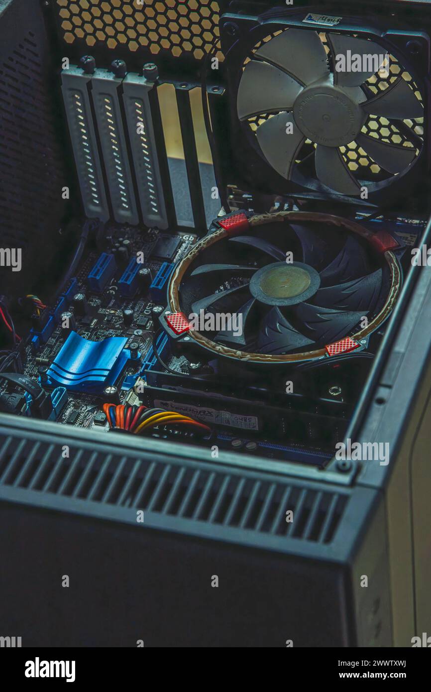 Vista ravvicinata dell'interno di un case di un computer desktop rotto, che mostra una scheda madre del computer, una ventola della CPU e i relativi componenti. Foto Stock