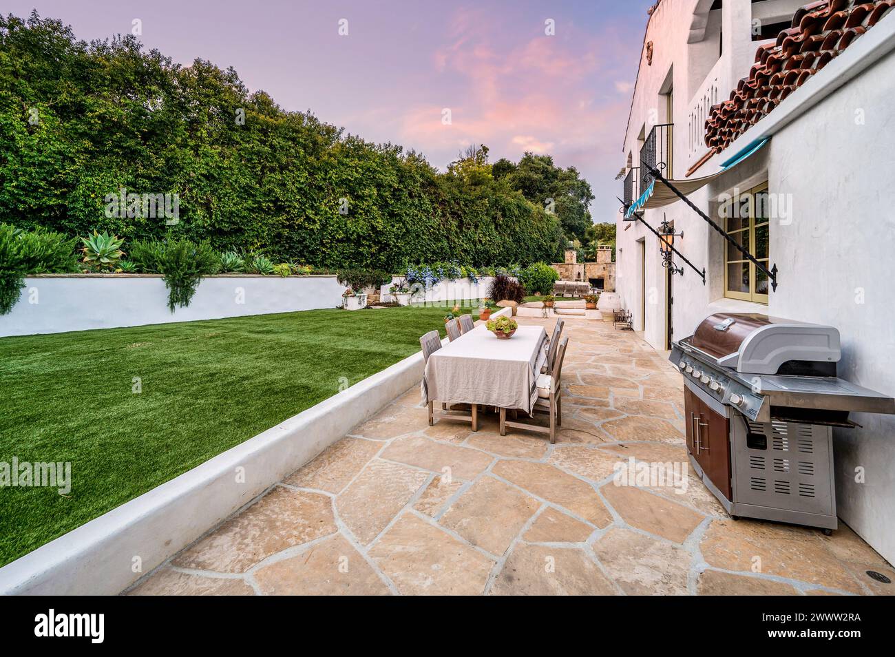 Un barbecue e un patio adagiati al centro di un lussureggiante giardino Foto Stock
