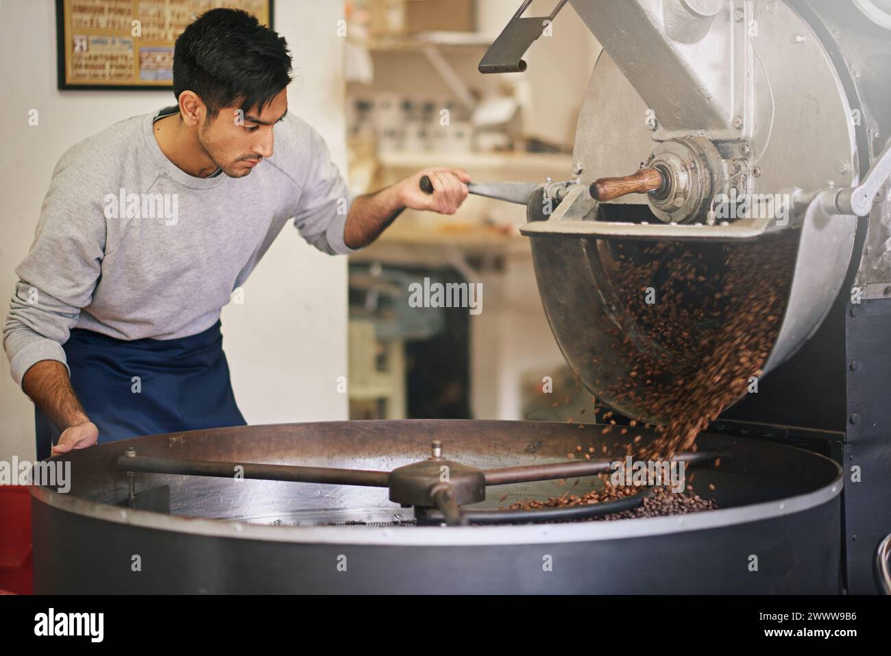 Caffetteria, piccola impresa e macchina per tostatura con miscelazione, produzione o controllo qualità. Imprenditore, barista o tostapane con fagioli Foto Stock