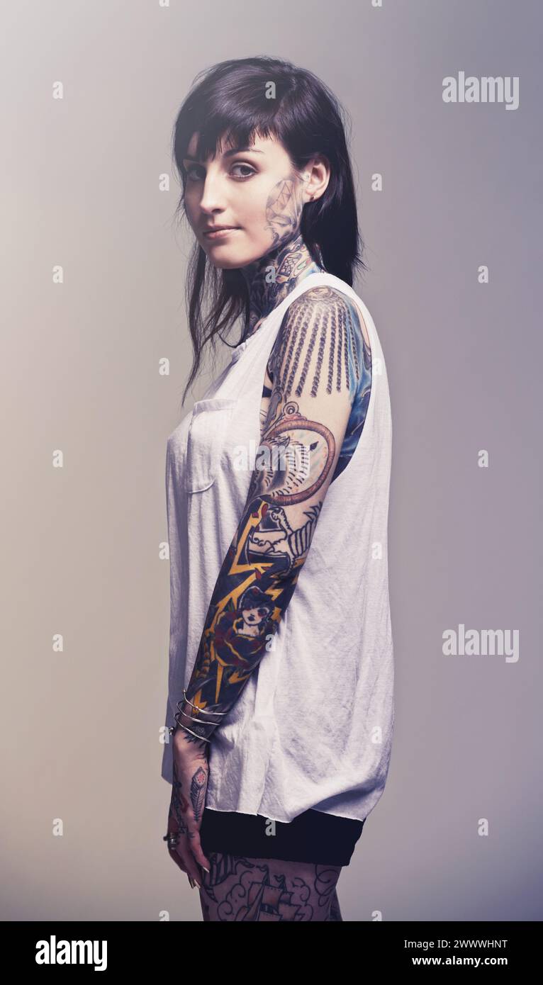 Ritratto, tatuaggio e cultura con donna, ribelle e punk rock su sfondo grigio studio. Heavy metal, arte e modello con fiducia e orgoglio Foto Stock