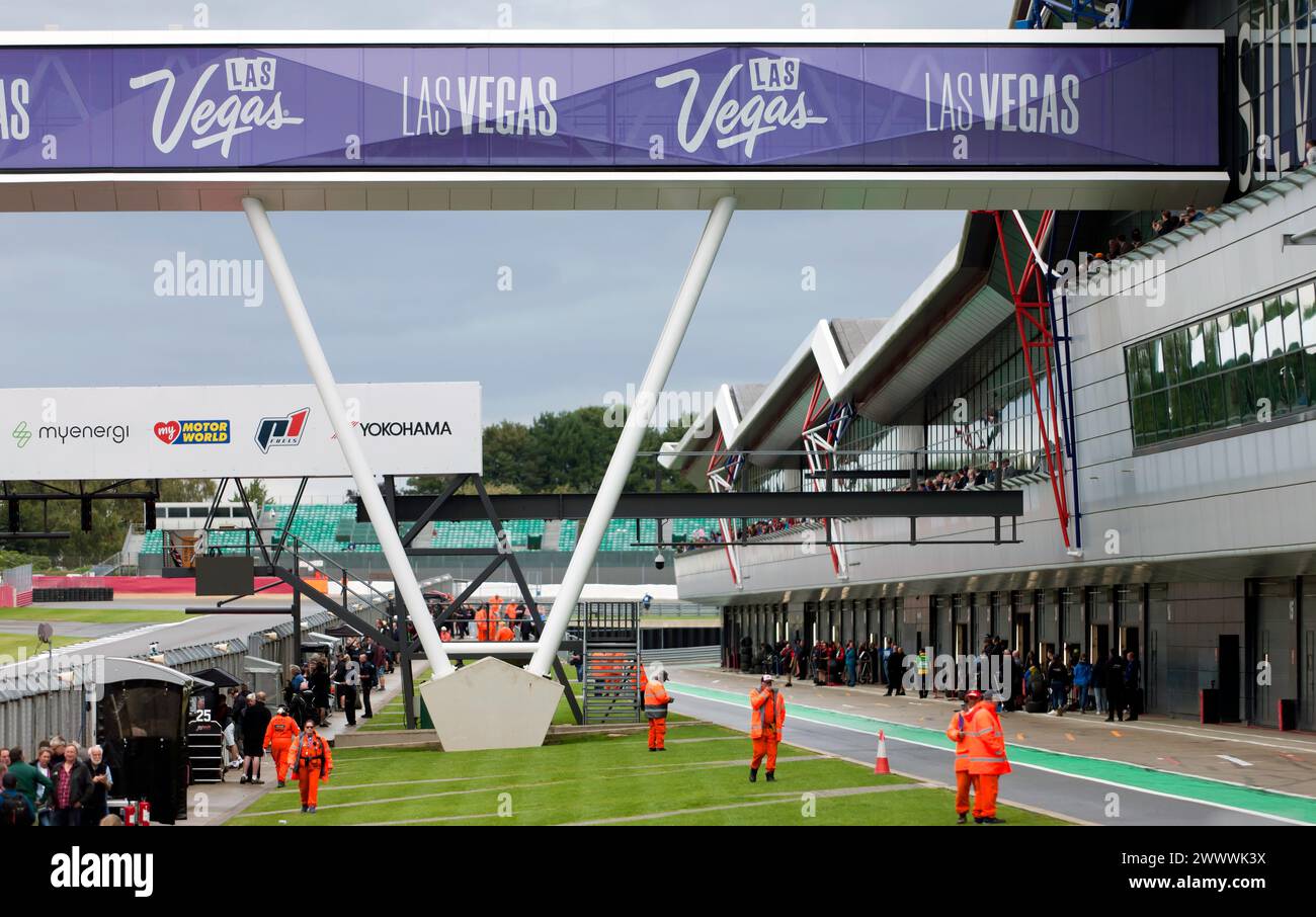 Silverstone Race Marshals si allineano lungo la pit Lane internazionale, per l'inizio della Masters Racing Legends Formula One Race ('66 -'85). Foto Stock