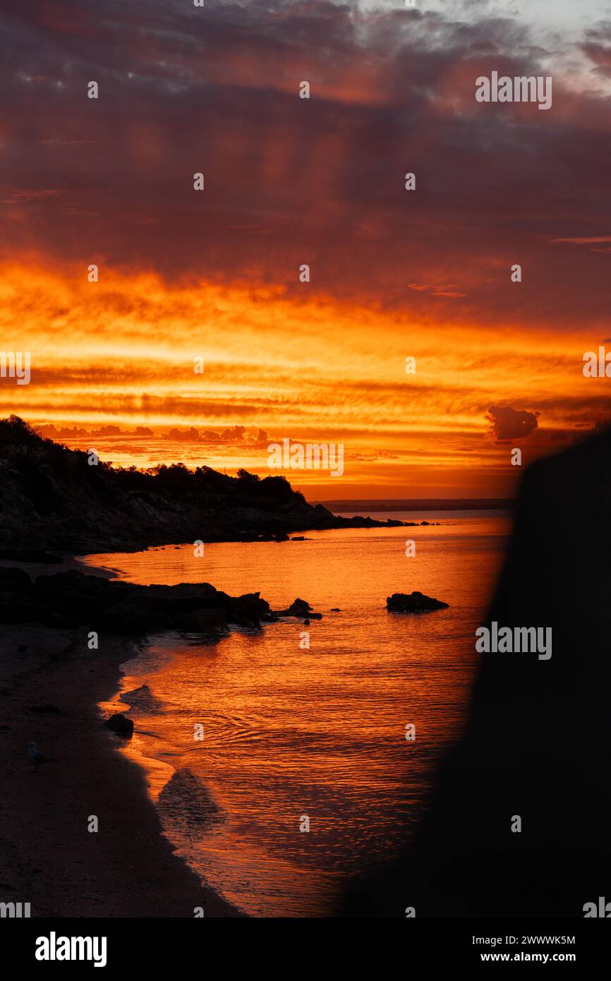 Tramonto sulla spiaggia oceanica con rocce in acqua Foto Stock