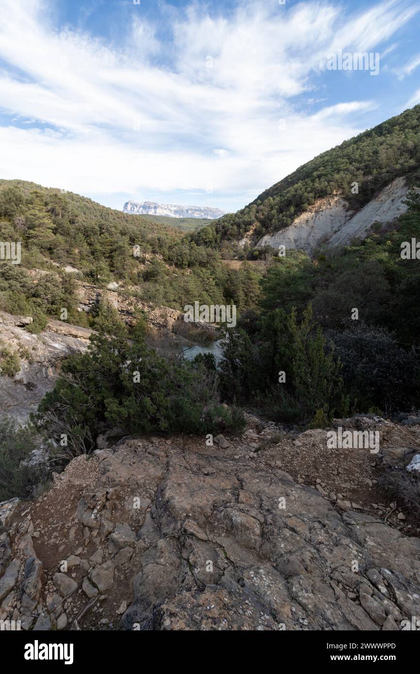 paesaggio aspro che mostra la serena bellezza di una valle verde circondata da ripide scogliere sotto un cielo blu Foto Stock