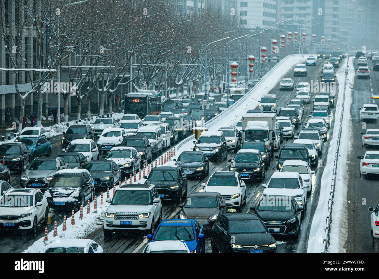 Una strada della città ricoperta di neve con traffico e linee di traffico a Wuhan, Cina. Foto Stock