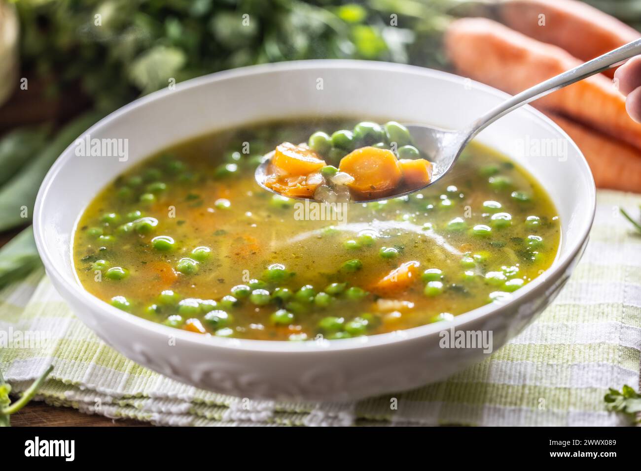Zuppa di verdure sane con verdure fresche di primavera. Vista ravvicinata di un cucchiaio pieno di zuppa calda. Foto Stock