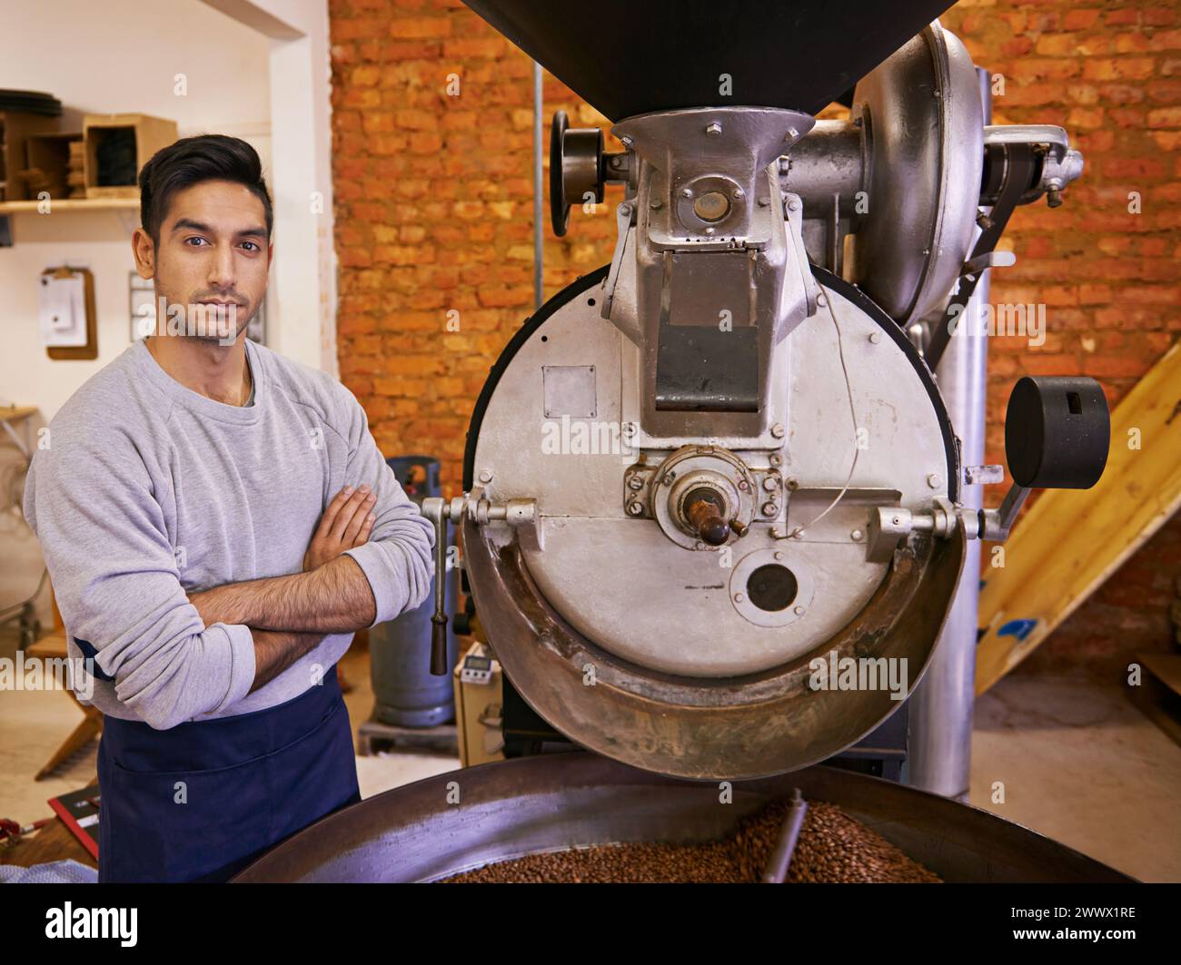 Caffè, piccola impresa e ritratto dell'uomo con tostatrice per frullare, produrre e controllare la qualità. Imprenditore, barista e braccia incrociate Foto Stock