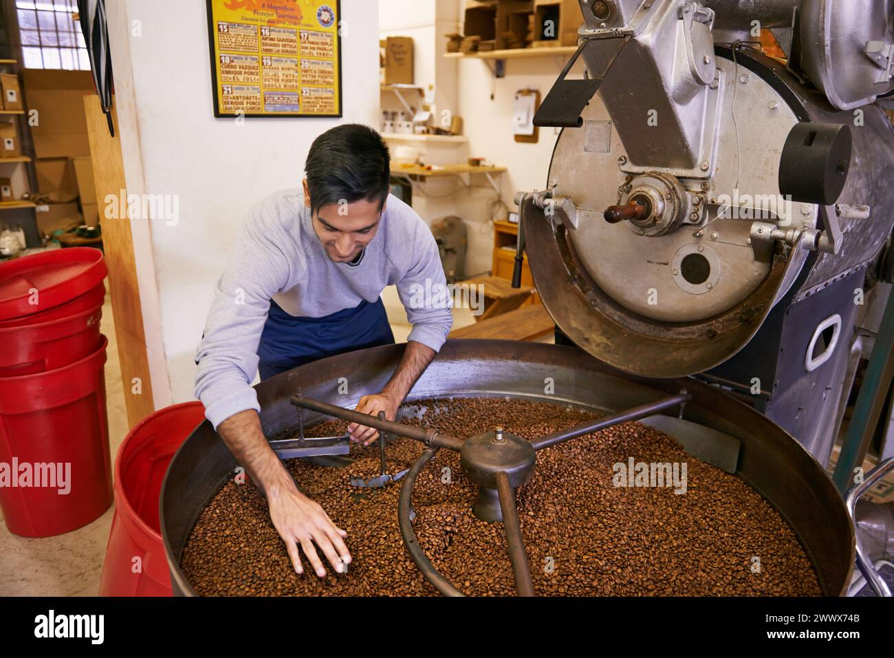 Chicchi di caffè, miscela e uomo con macchina per tostatura con piccole imprese, produzione e controllo qualità. Imprenditore, barista o lavoratore con grano Foto Stock