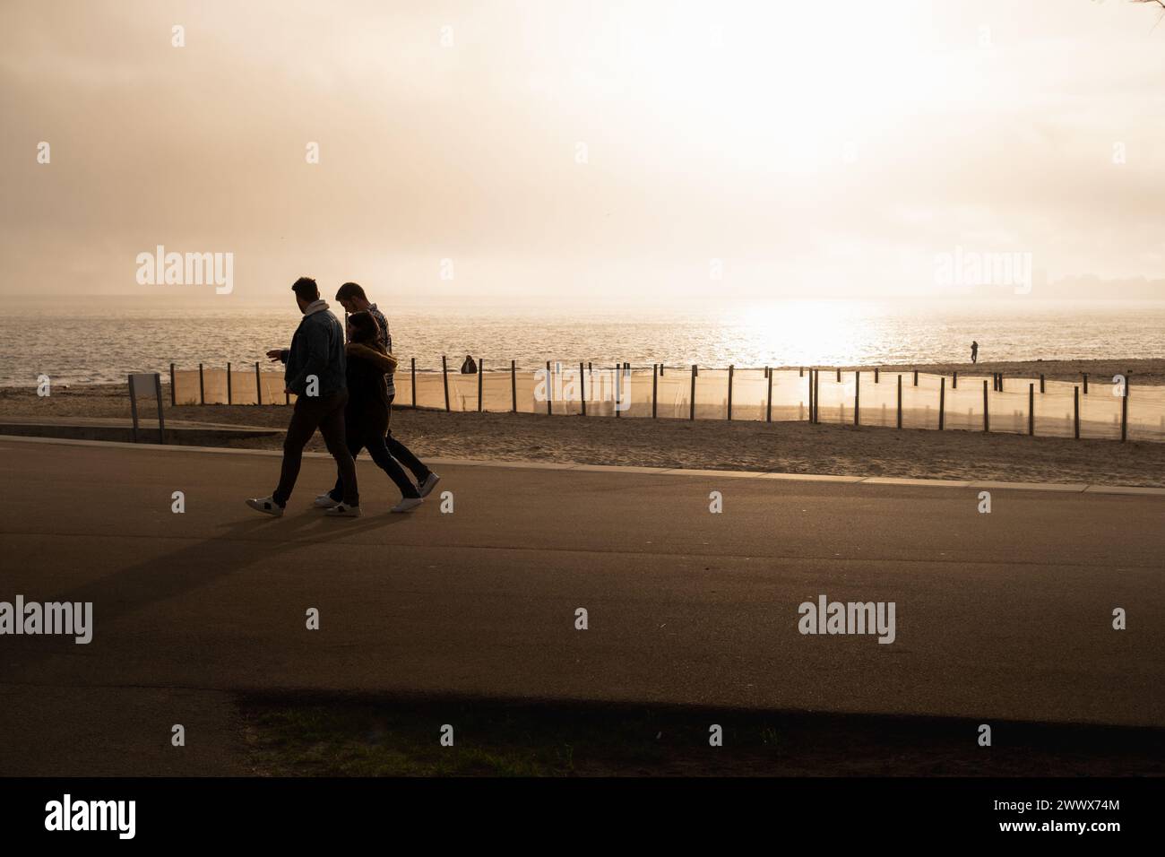 La gente passeggia lungo il lungomare durante un bellissimo tramonto Foto Stock