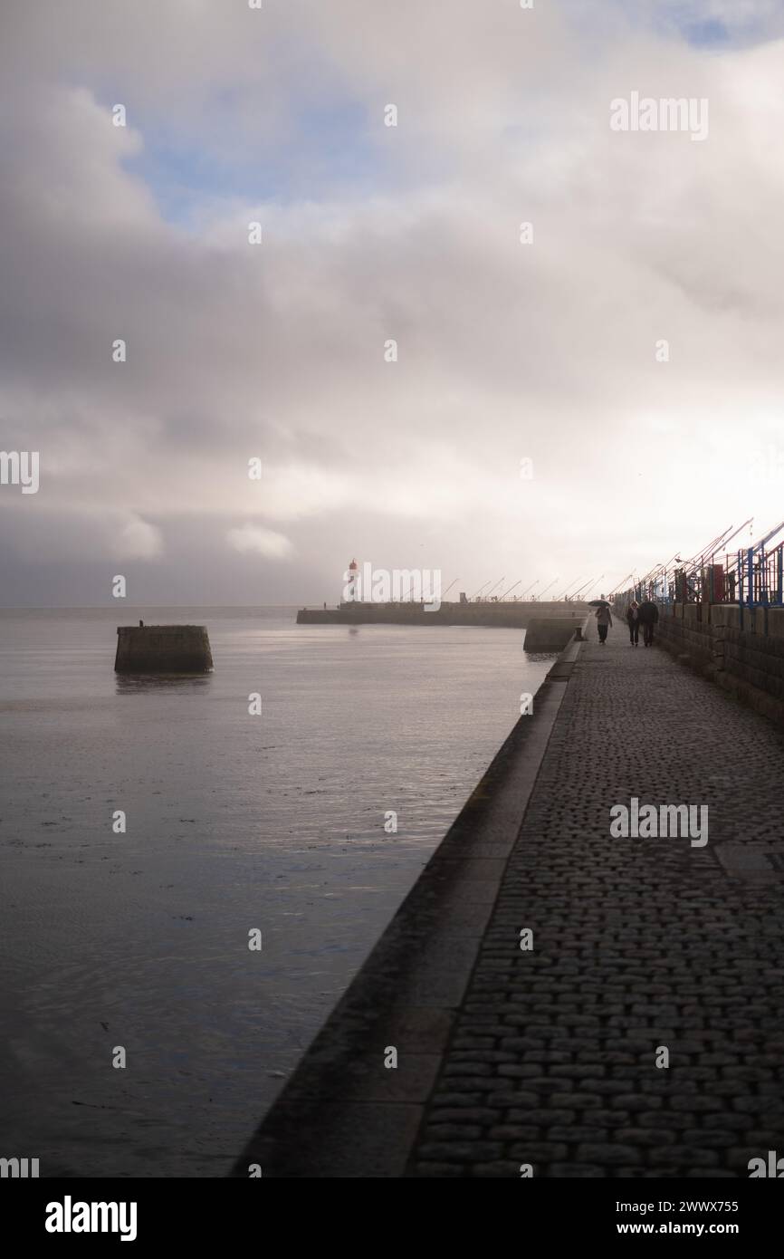 Un gruppo di persone che camminano lungo la banchina accanto al mare. Saint Nazaire Foto Stock