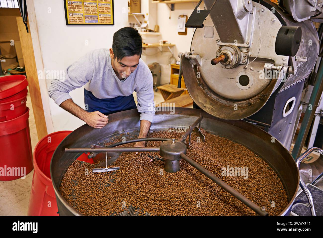Caffè, controllo di qualità e uomo con macchina per tostatura con miscelazione, produzione e piccole imprese. Imprenditore, barista o persona con fagioli a. Foto Stock