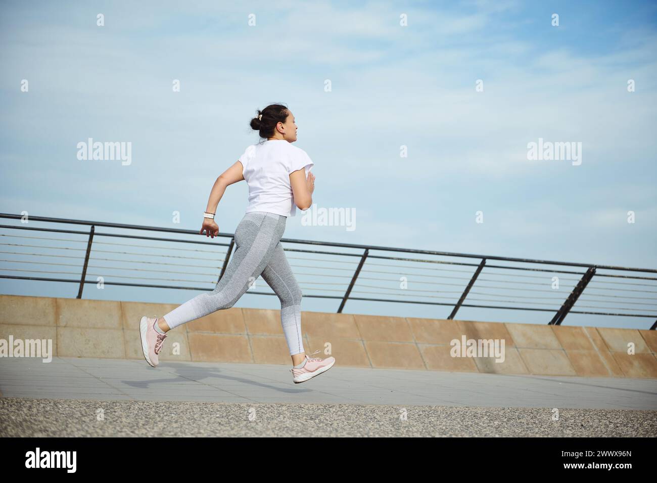 Vista dal retro di una atleta sportiva, jogger runner che fa l'allenamento cardio e corre all'aperto sul ponte della città. Fitness. Sport. Attivo sano l Foto Stock
