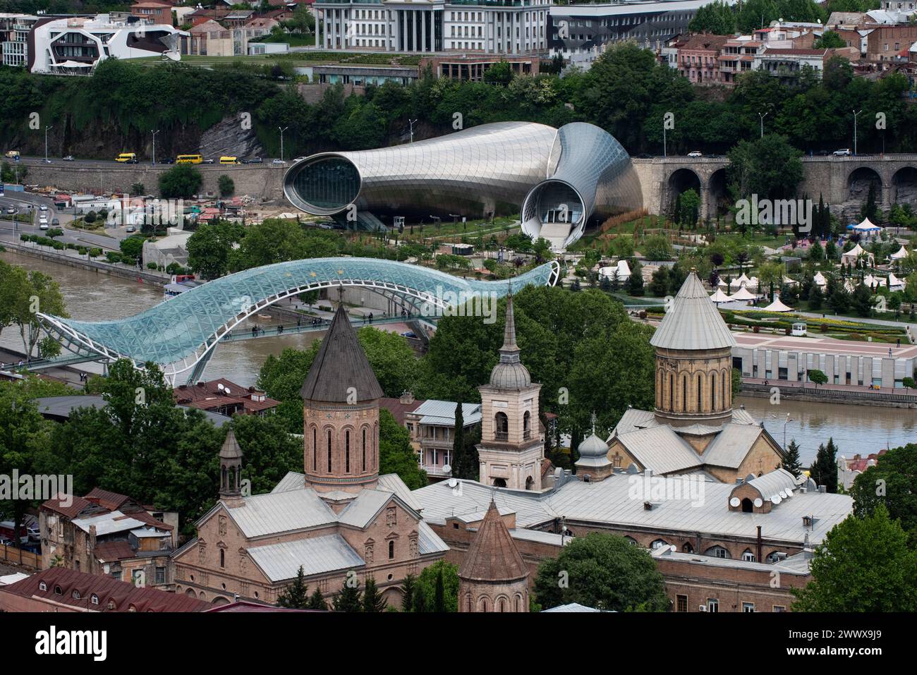 Vista aerea di Tbilisi, capitale della Repubblica di Georgia, con il moderno ponte pedonale in vetro che attraversa il fiume Kura attraverso la città Foto Stock