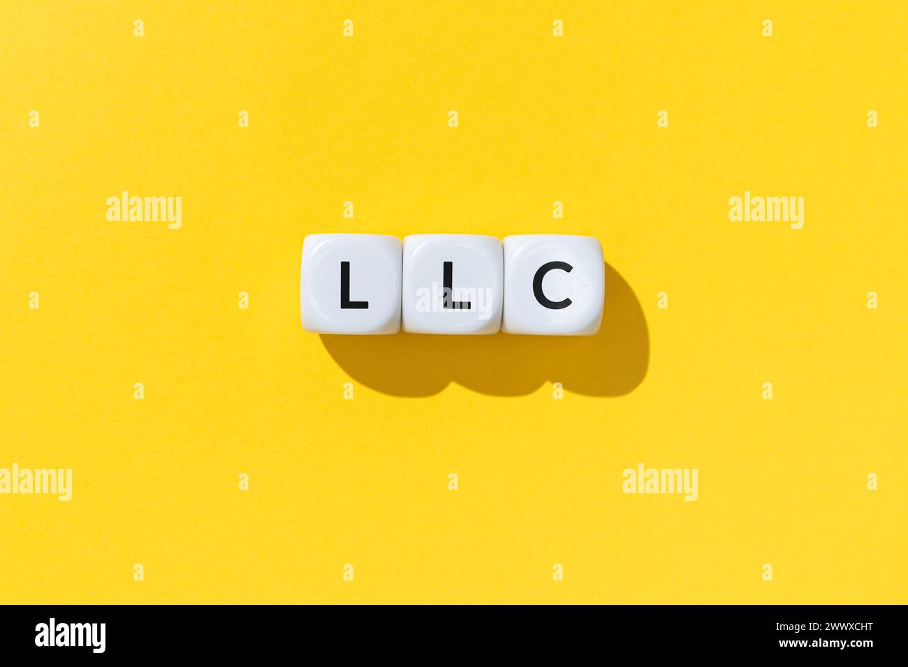 LLC o Limited Liability Company testo su blocchi cubi bianchi isolati su sfondo giallo Foto Stock