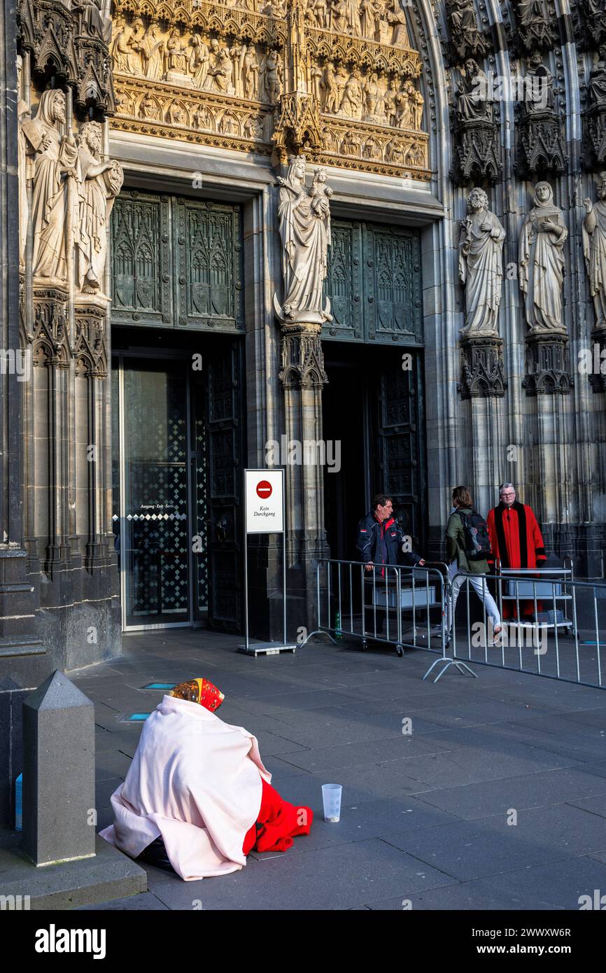 Una donna mendicante siede di fronte al portale principale della cattedrale, Colonia, Germania. eine Bettlerin sitzt vor dem Hauptportal des Doms, Koeln, Deutschl Foto Stock