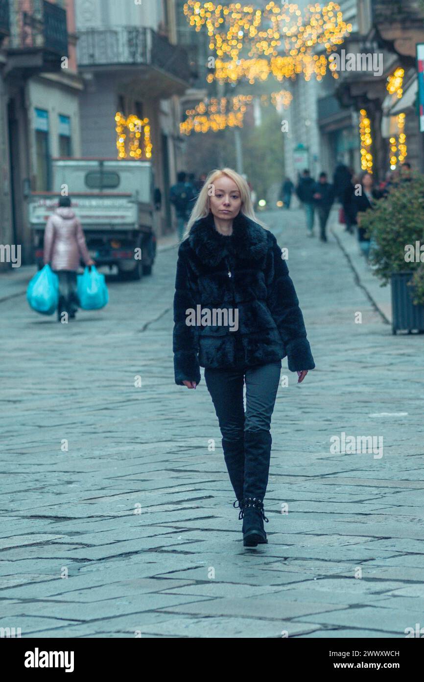 Immagine vibrante di una donna in un cappotto di pelliccia che cammina su una strada della città la sera Foto Stock