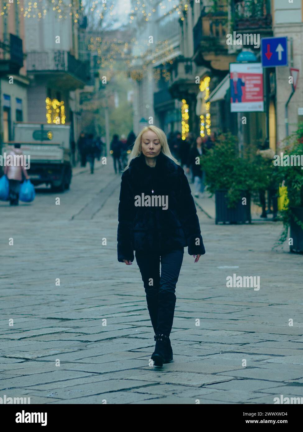 Donna con un cappotto di pelliccia che cammina su una strada della città con un colore verde acqua durante il giorno Foto Stock