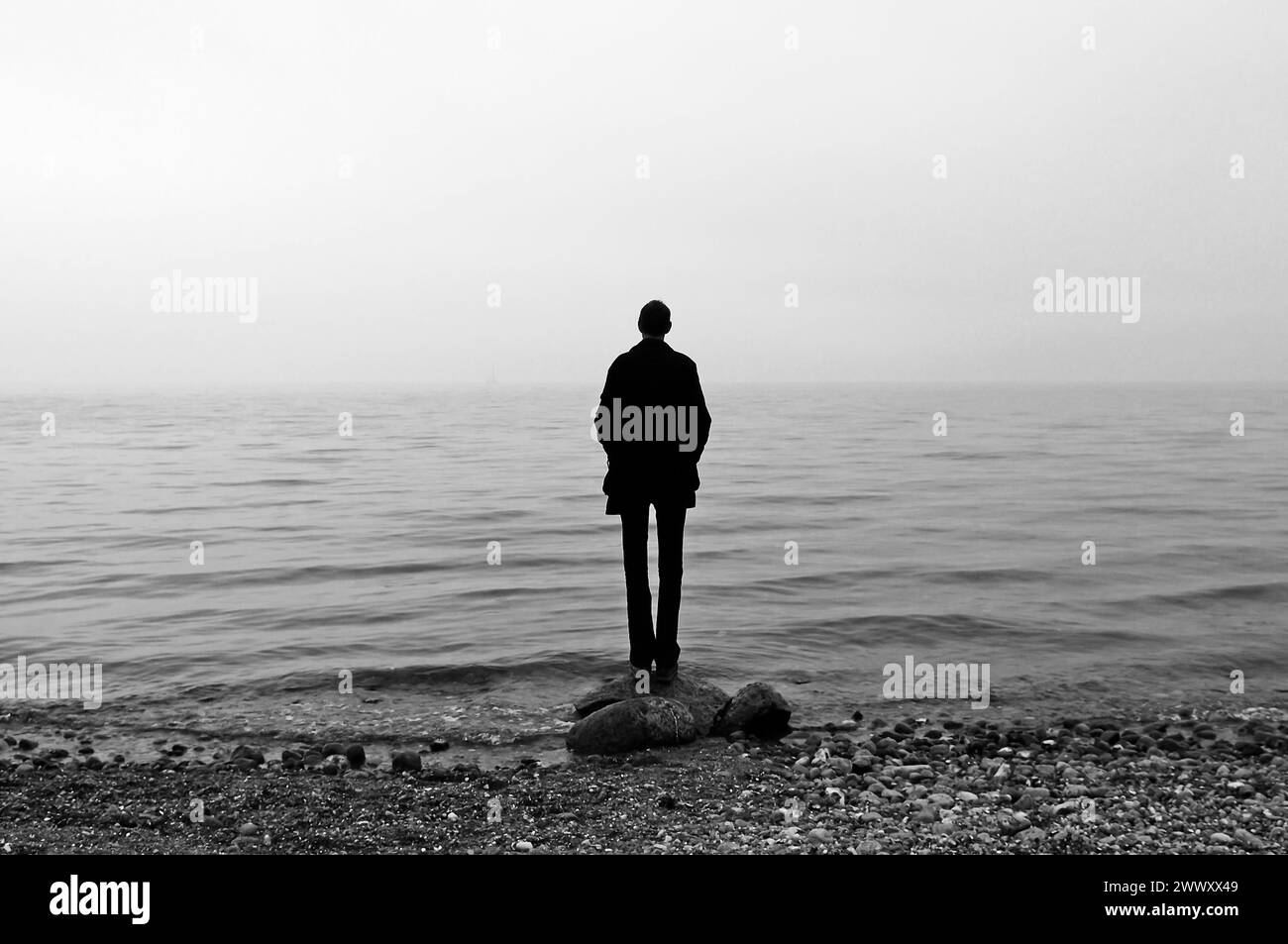 Il giovane uomo si erge sulla spiaggia con il tempo nuvoloso e guarda al Mar Baltico, al Gross Schwansee, al Meclemburgo-Vorpommern, in Germania Foto Stock