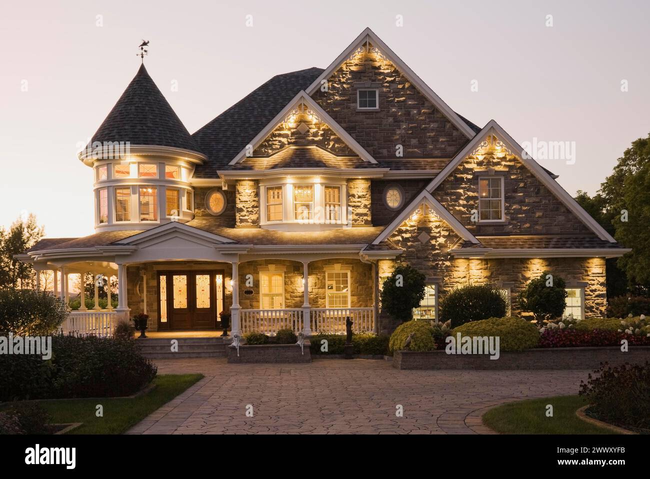 Elegante pietra grigia con rifiniture bianche e tetto blu con tegole di asfalto facciata vittoriana al crepuscolo in estate, Quebec, Canada Foto Stock