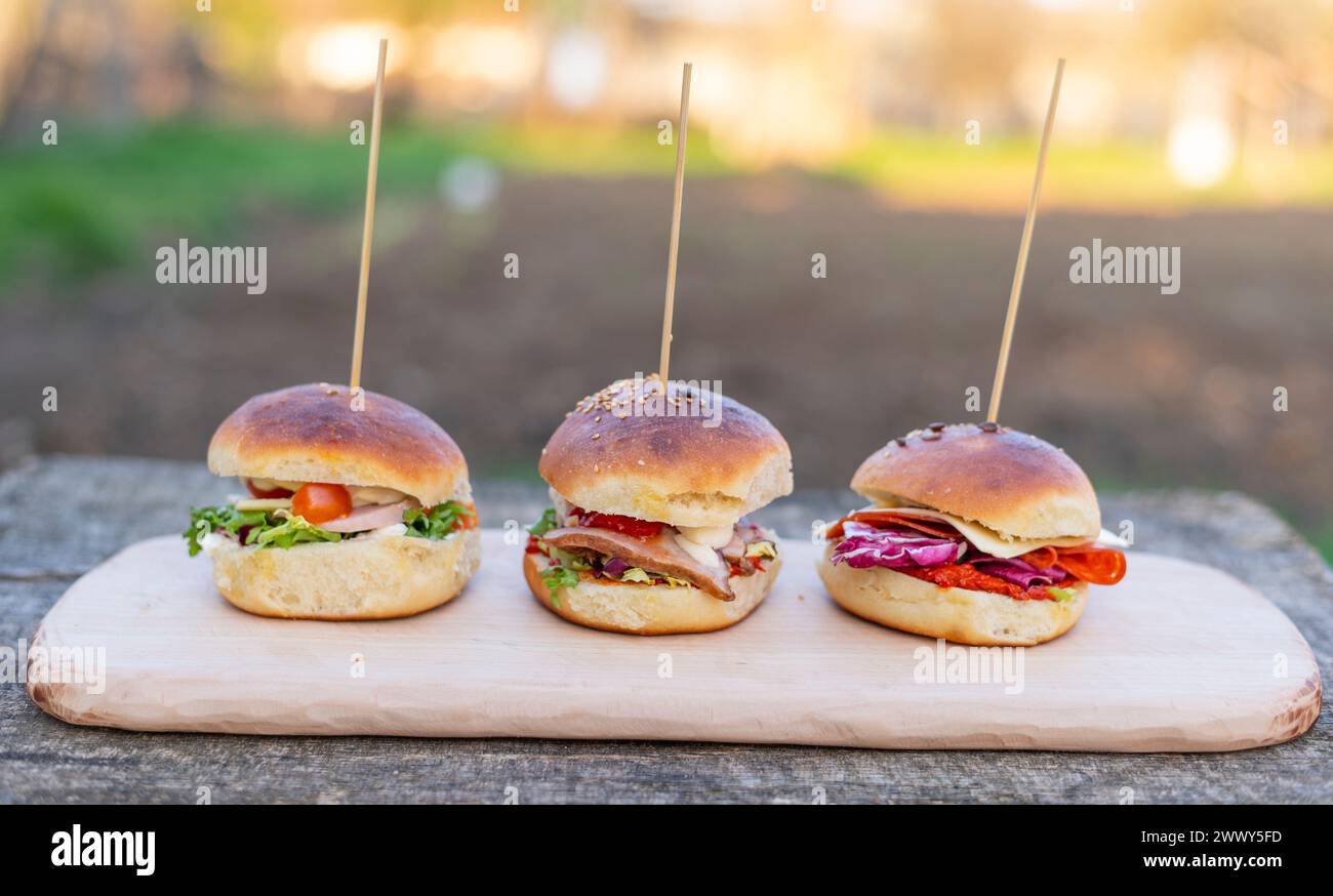 Tre panini con pancetta e verdure varie su un tavolo di legno. Foto Stock
