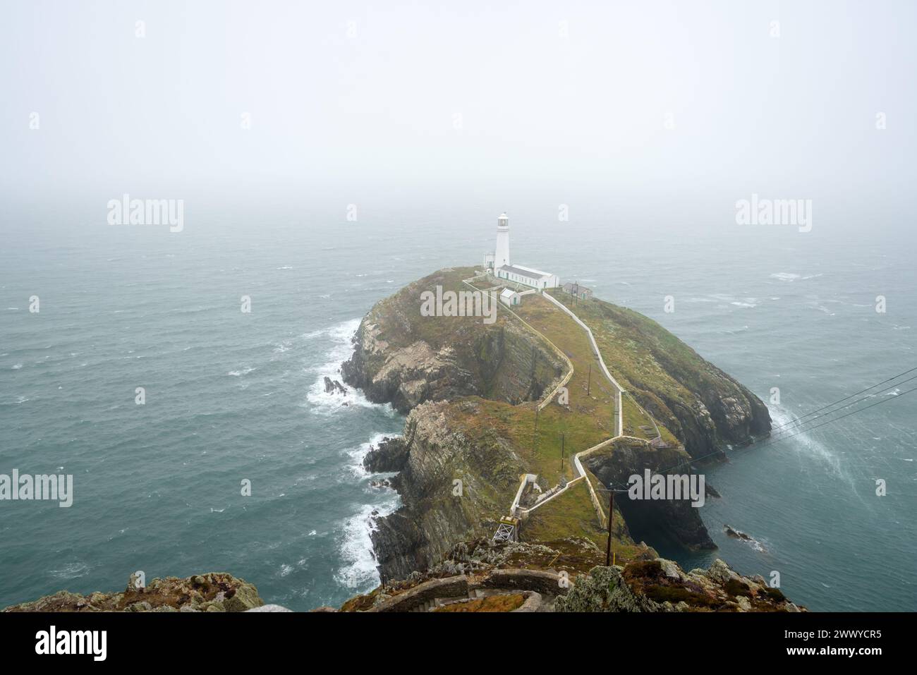 Faro storico sulla cima di una piccola isola al largo della costa del Galles in una nebbiosa giornata estiva Foto Stock