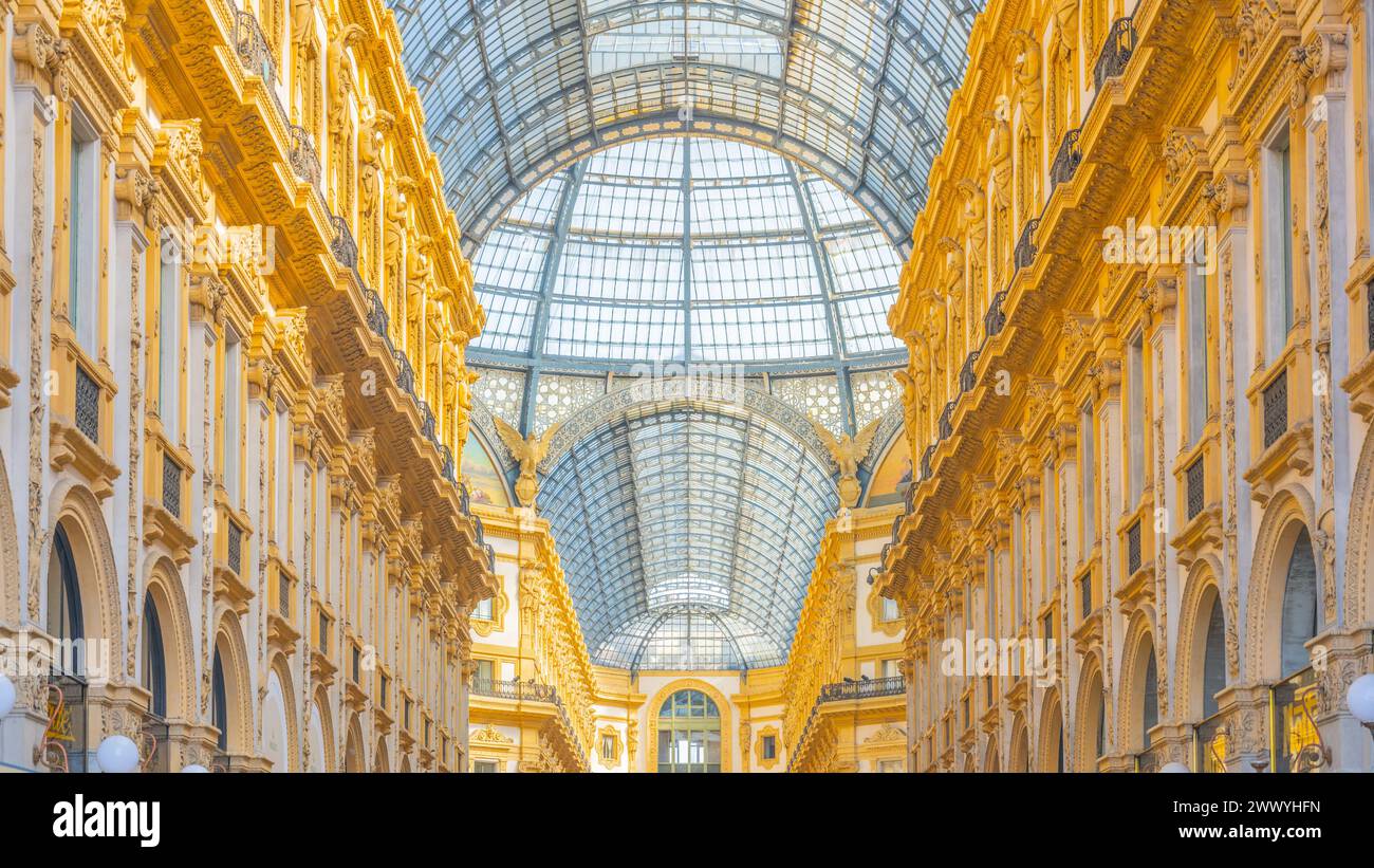 Una squisita cattura della Galleria Vittorio Emanuele II a Milano, Italia. L'immagine mostra l'intricato soffitto a cupola di vetro, circondato da un'architettura dorata ornata, che riflette la grandezza di questo monumento storico Foto Stock