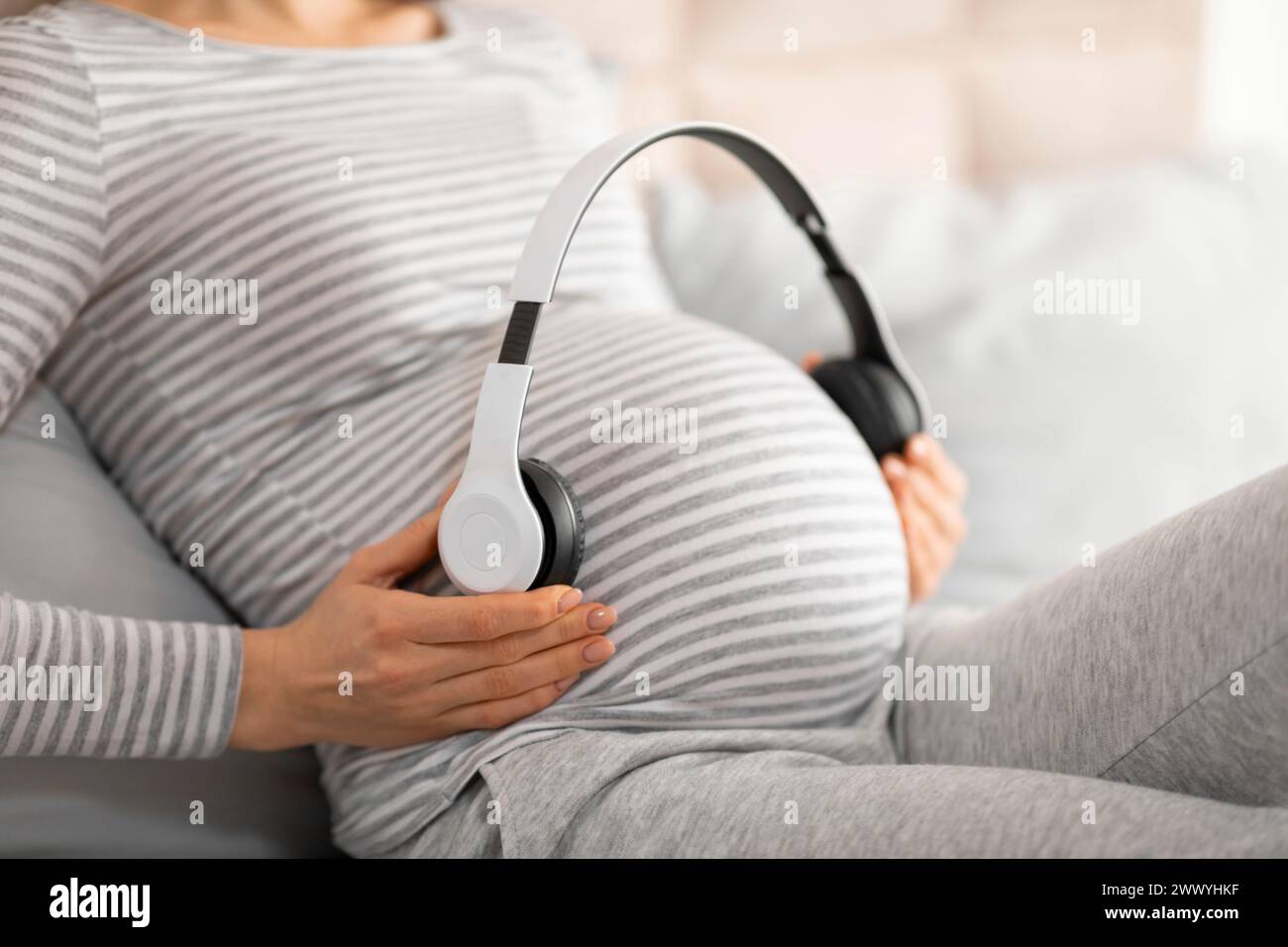 La mamma incinta sente il calcio del bambino con le cuffie Foto Stock