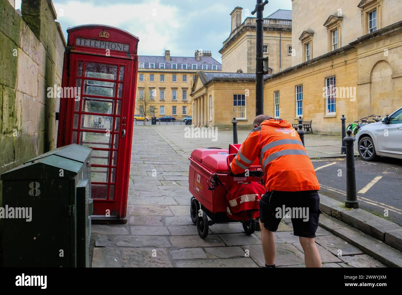 Marzo 2024 - il postino della Royal mail spinge il suo carrello su una collina nella città di Bath, Inghilterra, Regno Unito. Foto Stock