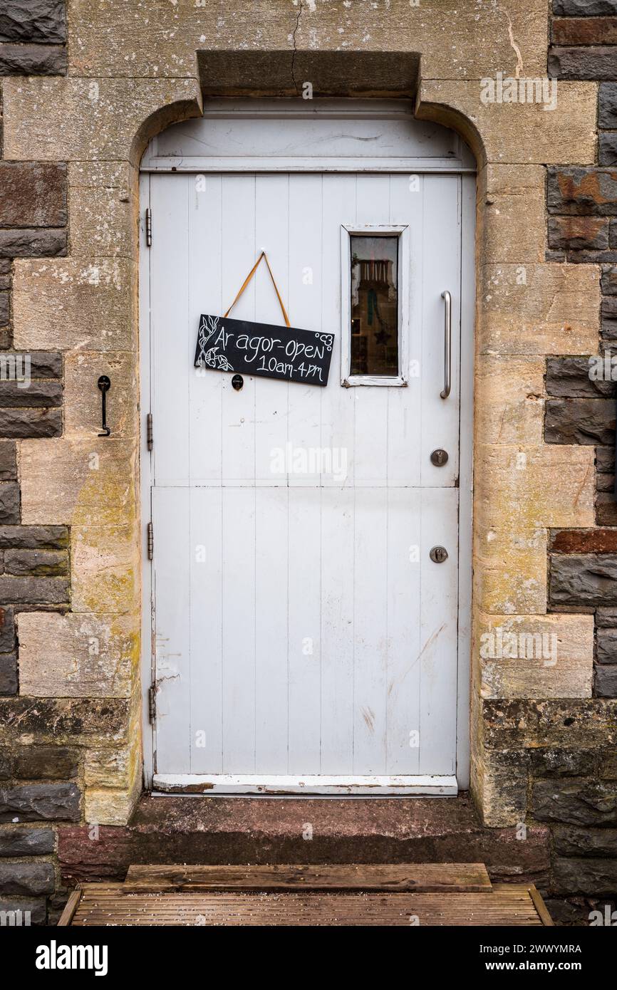 Porta gotica con una porta alberata bianca e un cartello bilingue con orari di apertura in gallese e inglese. Cardiff, Galles, Regno Unito Foto Stock