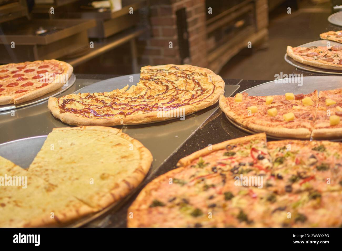 Immagine che mostra una selezione di pizze gourmet con ingredienti diversi, con un'atmosfera calda e accogliente. Le pizze sono appena sfornate e pronte per essere Foto Stock