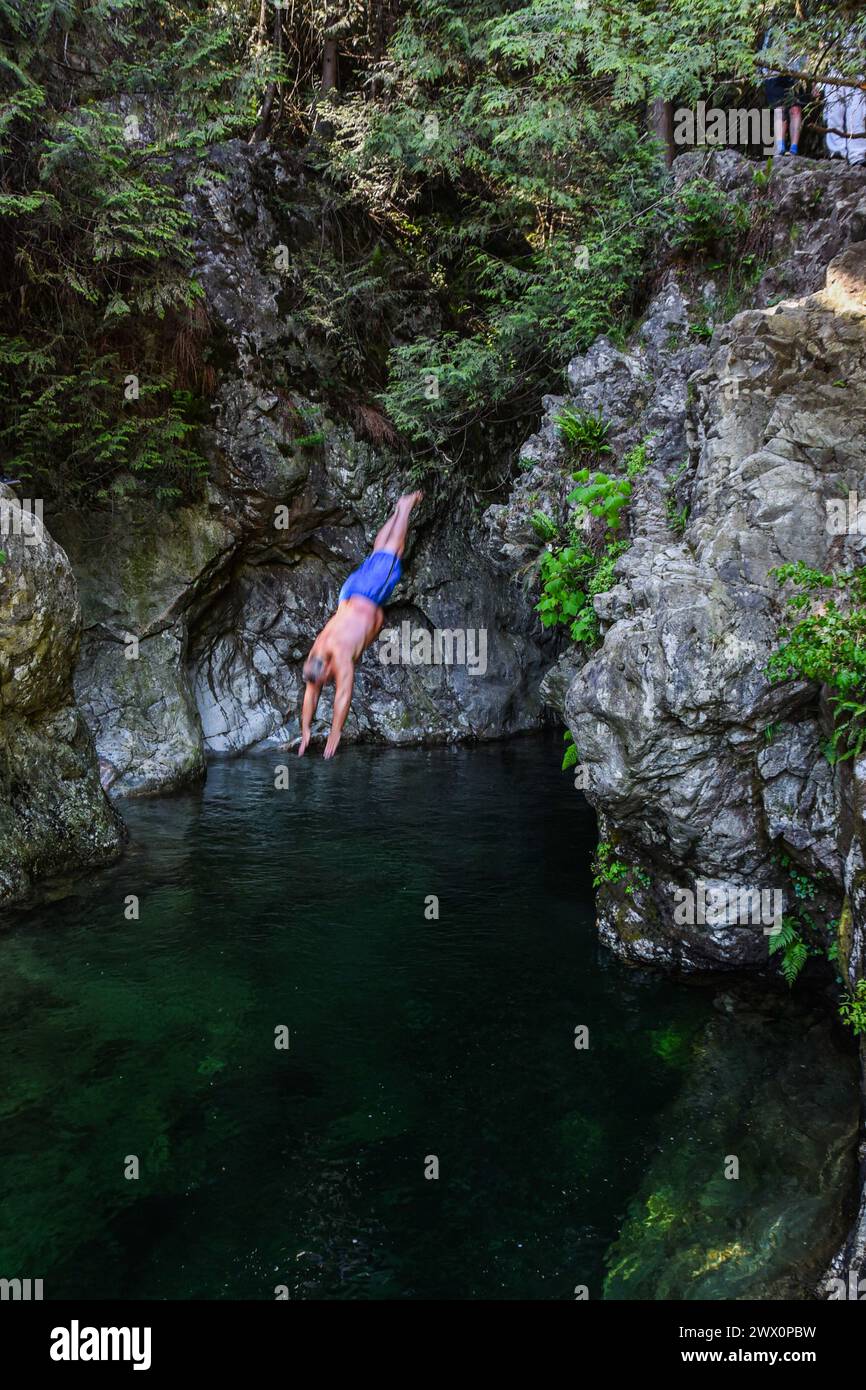 Uomo che si tuffa in una piscina d'acqua nel Lynn Canyon, North Vancouver Foto Stock