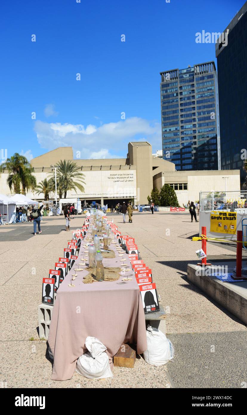 Un'installazione di un tavolo da pranzo di sabato con sedie per gli ostaggi a Gaza in Piazza degli ostaggi, Tel-Aviv, Israele. Foto Stock
