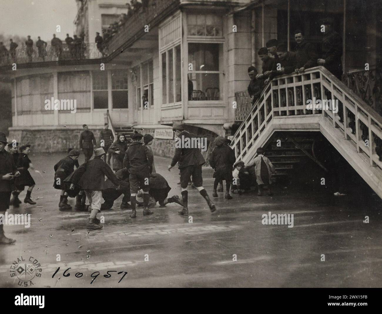 UOMINI della A.E.F. CHE SI GODONO la selvaggia corsa che i bambini francesi fanno inseguendo monete che i soldati stanno lanciando loro. Uscire dall'area. St Malo, Ille et Vilaine, Francia ca. 1919 Foto Stock