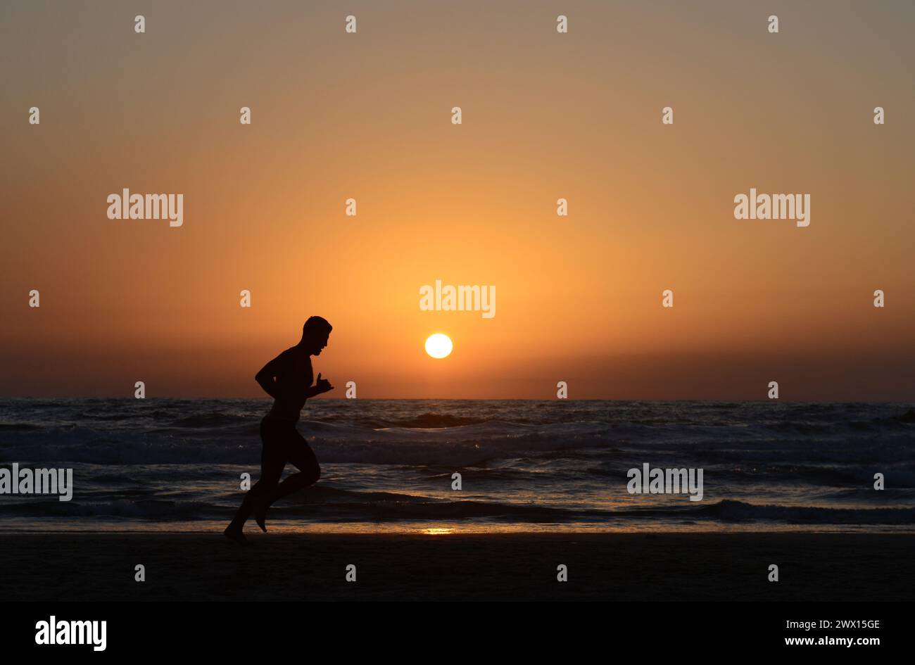 Jogging sulla spiaggia al tramonto a Tel Aviv, Israele. Foto Stock