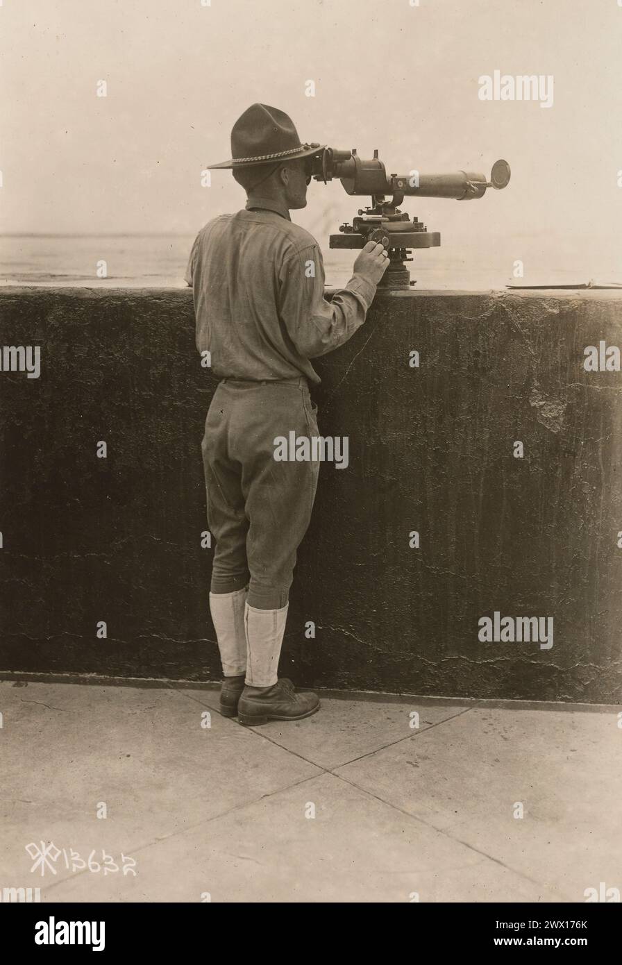 Un soldato alle operazioni di difesa costiera Fortress Monroe, Virginia, usa un mirino per osservare un colpo nell'acqua CA. 1918 Foto Stock