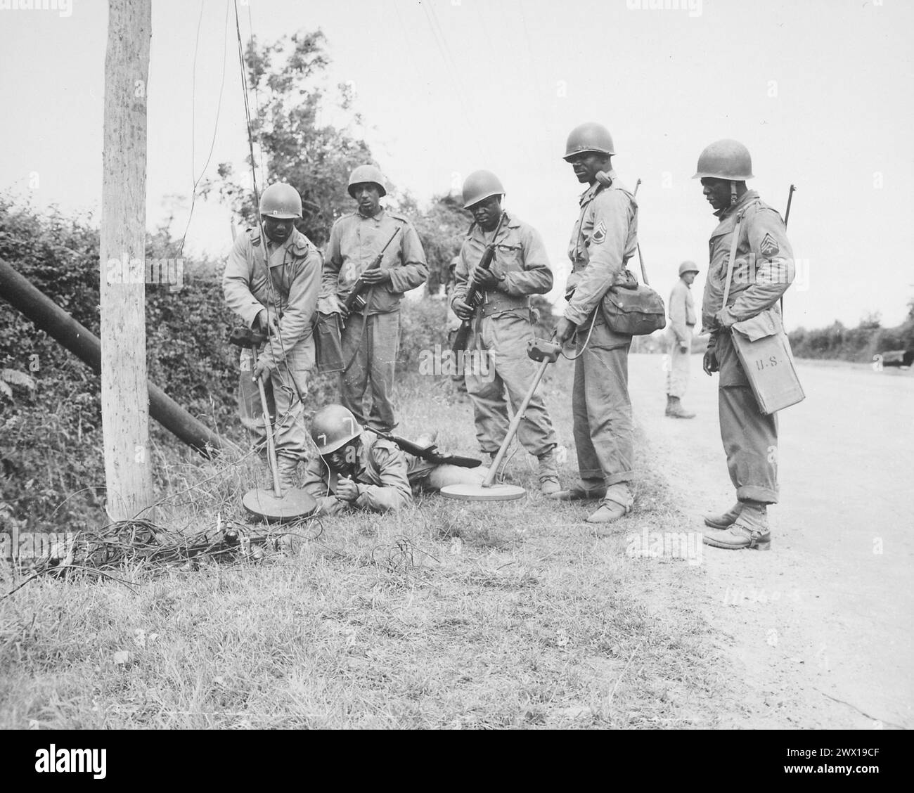 Questa squadra di rilevatori di mine sta dimostrando cosa fanno prima di andare a lavorare su o intorno ai pali telefonici in Francia CA. Luglio 1944 Foto Stock