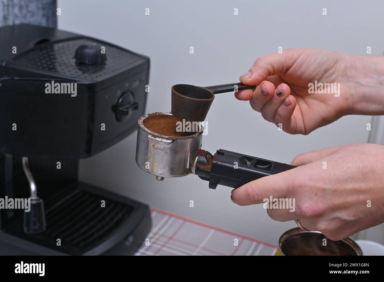 una donna prepara il caffè con una macchina per il caffè di casa Foto Stock