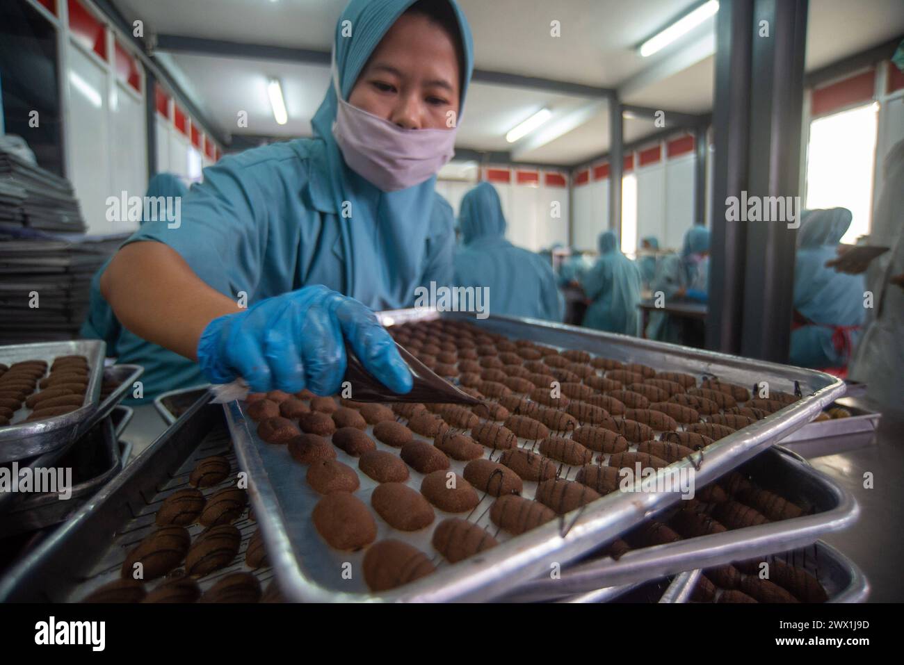 LA PRODUZIONE DI BISCOTTI PRIMA CHE i lavoratori di EID finiscano di produrre biscotti al cioccolato presso la fabbrica di biscotti J&C di Bandung, Giava Occidentale, Indonesia, 27 marzo 2024. Durante il mese sacro del Ramadan 1445 H, i biscotti J&C mirano a produrre da 500 a 600 dozzine di biscotti o 10.000 vasetti al giorno. I biscotti sono una delle specialità di Eid al-Fitr. IMAGO/KHAIRIZAL MARIS Bandung West Java Indonesia Copyright: XKharizalxMarisxKhairizalxMarisx COOKIES PRODUCTION PRIMA DI EID 1 Foto Stock