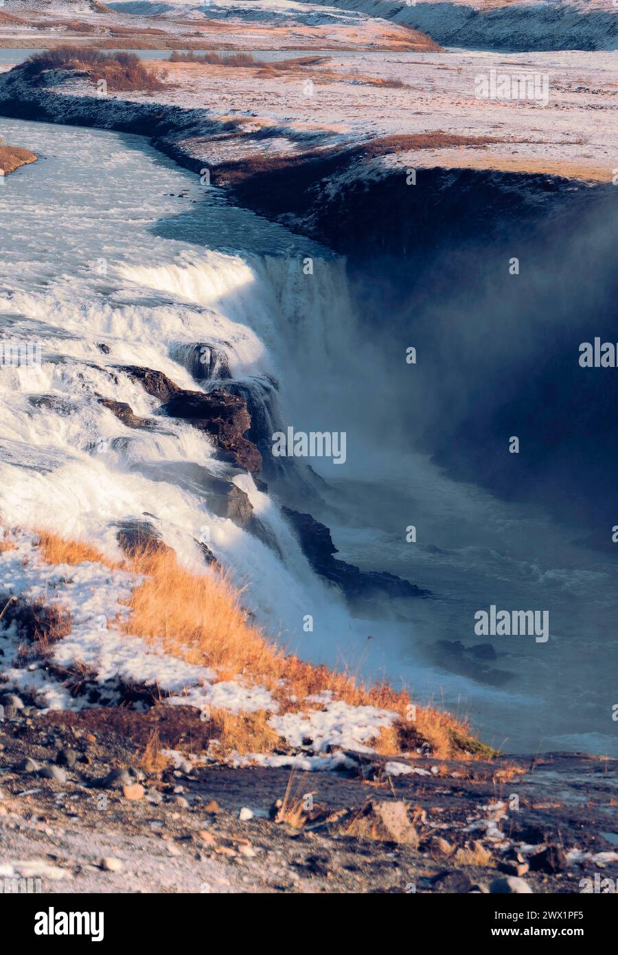 Una cascata è visibile in lontananza, con la neve che copre il terreno. Concetto di meraviglia e meraviglia per la bellezza naturale della scena. Il cerchio d'Oro, io Foto Stock
