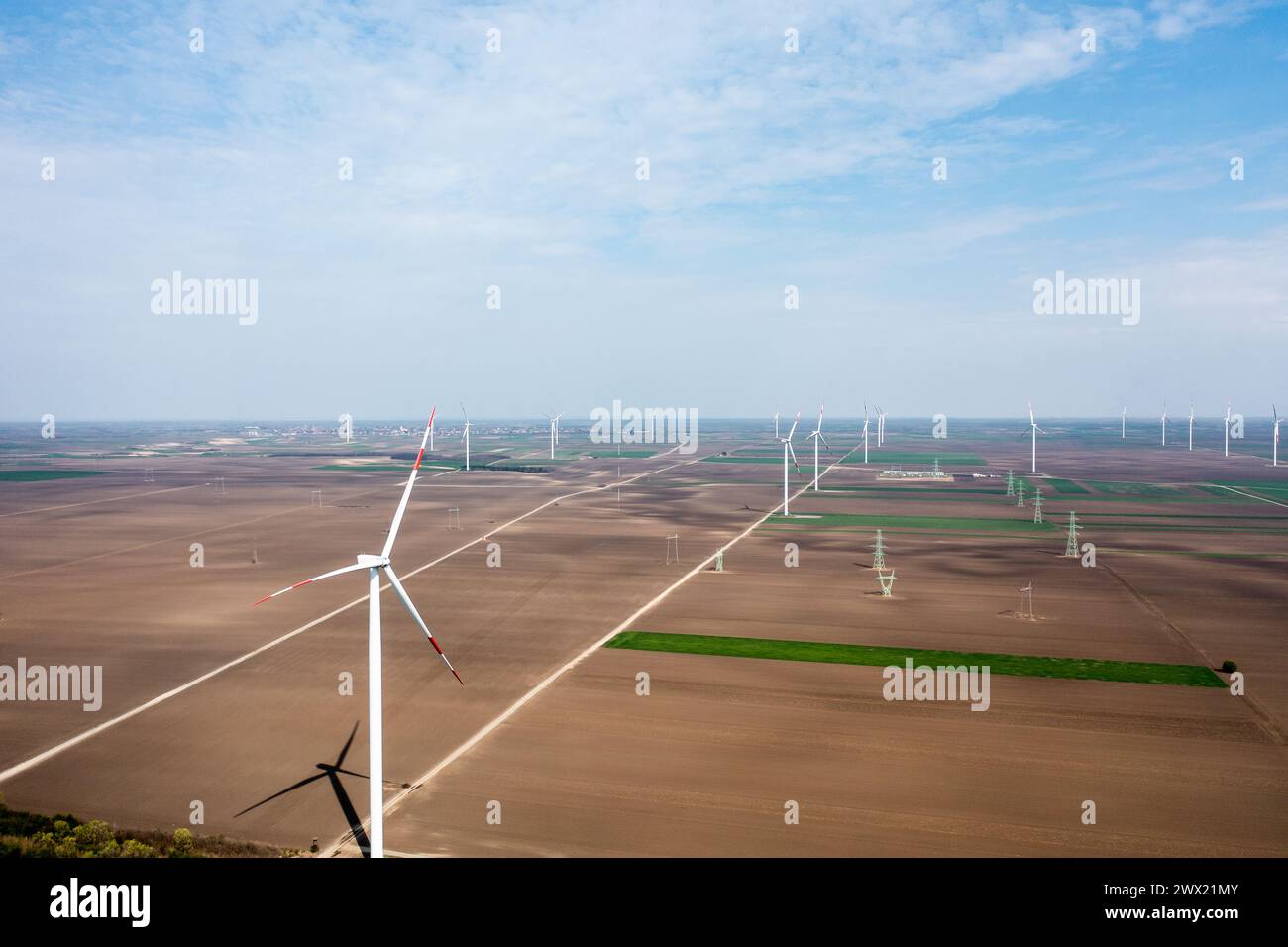 Le file su file di torreggianti turbine eoliche dominano il paesaggio, raccogliendo energia durante le pause del giorno Foto Stock