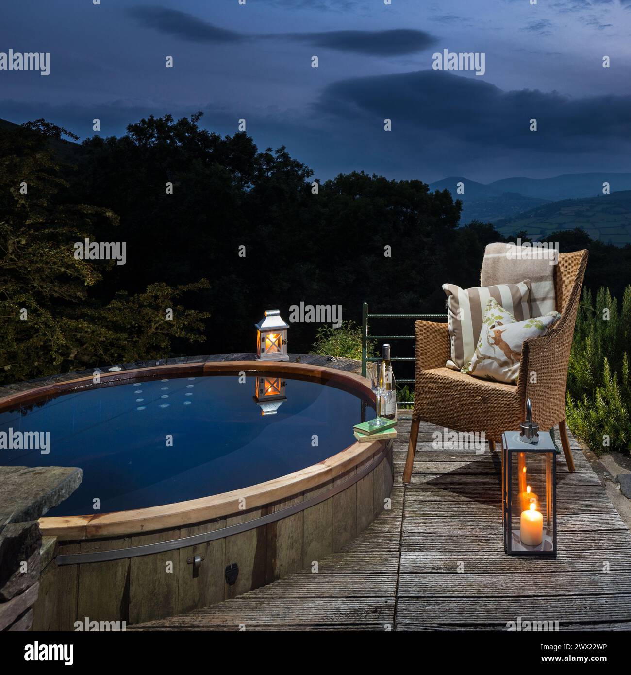 Una vasca idromassaggio su una terrazza in legno in una casa vacanze in Galles che si affaccia sulla campagna la sera Foto Stock