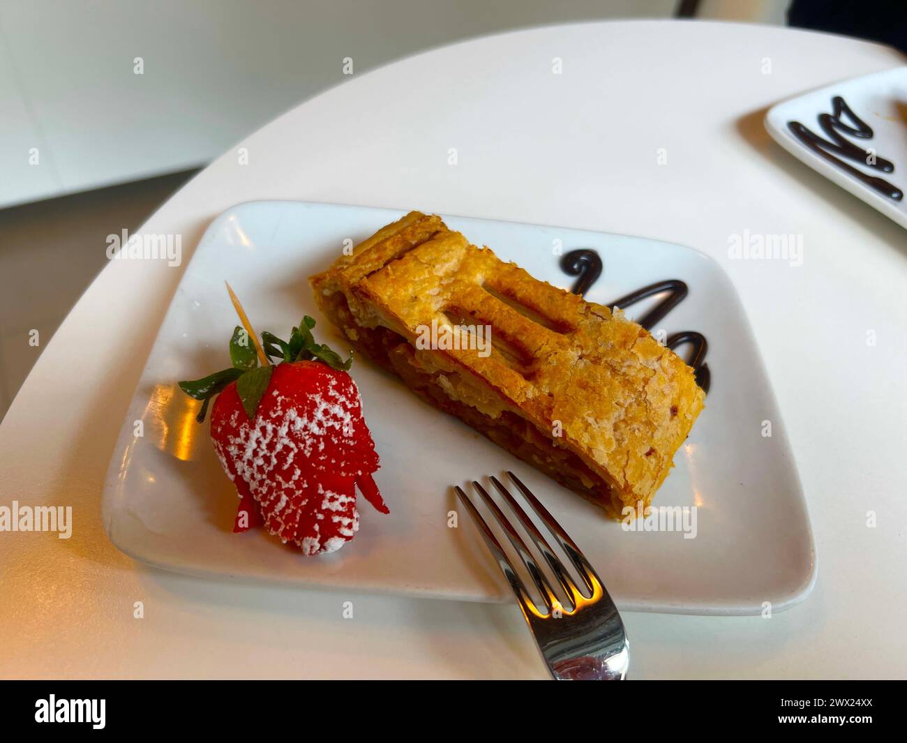 Strudel con mele e decorato con fragole e sciroppo al cioccolato Foto Stock
