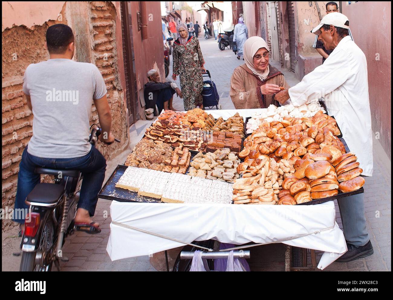 Una donna compra qualcosa di dolce in una strada vendendo nella medina di Marrakech in Marocco. fotografia vvbvanbree Foto Stock