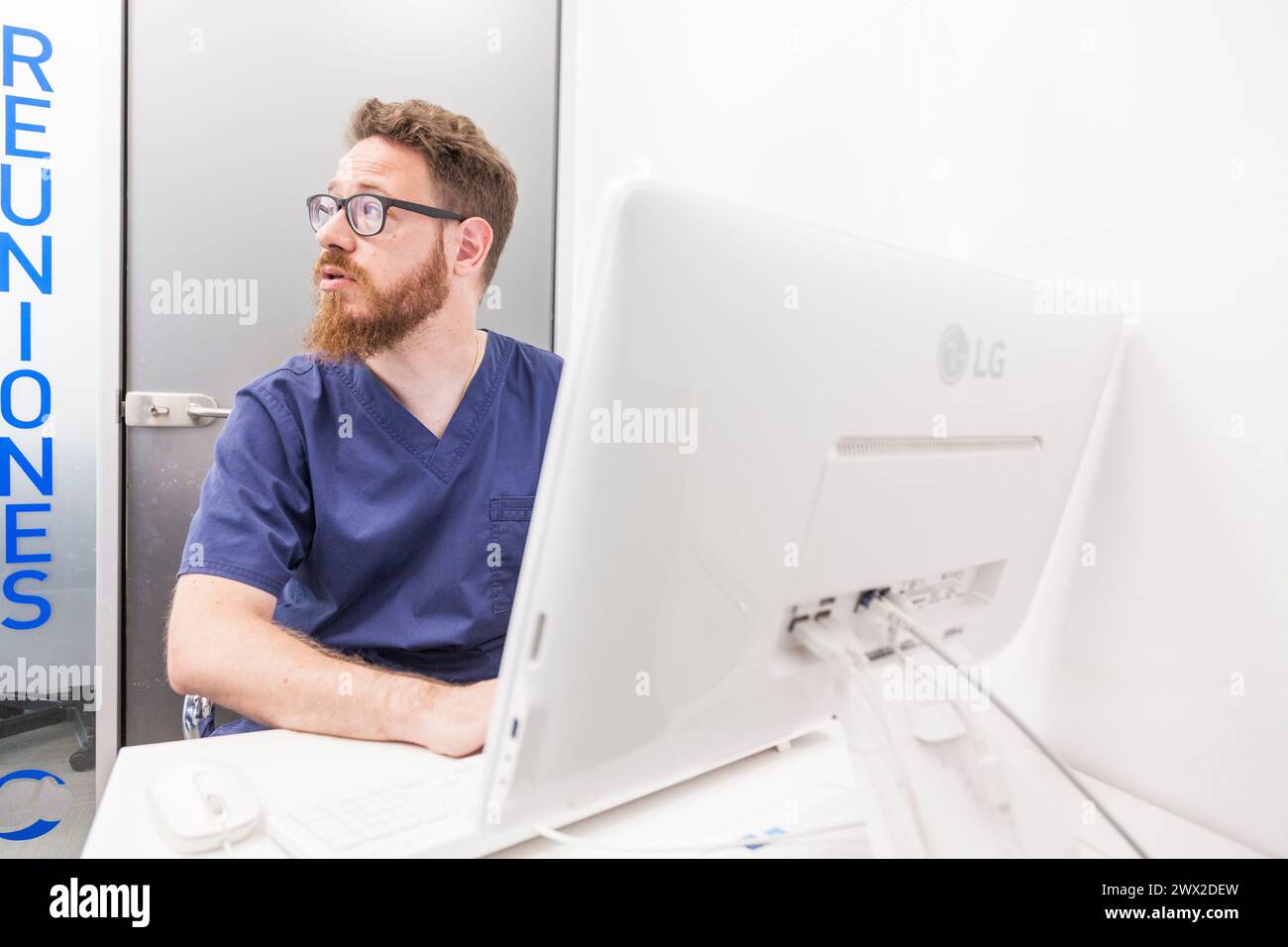Medico redhead male che lavora con il suo portatile durante la consultazione. Foto Stock