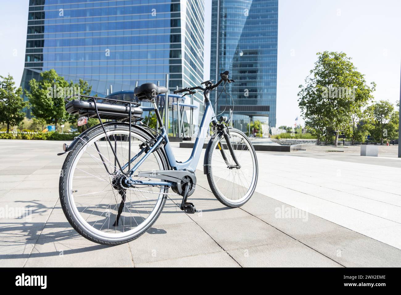 bicicletta elettrica di fronte alle torri dell'ufficio nella grande città Foto Stock