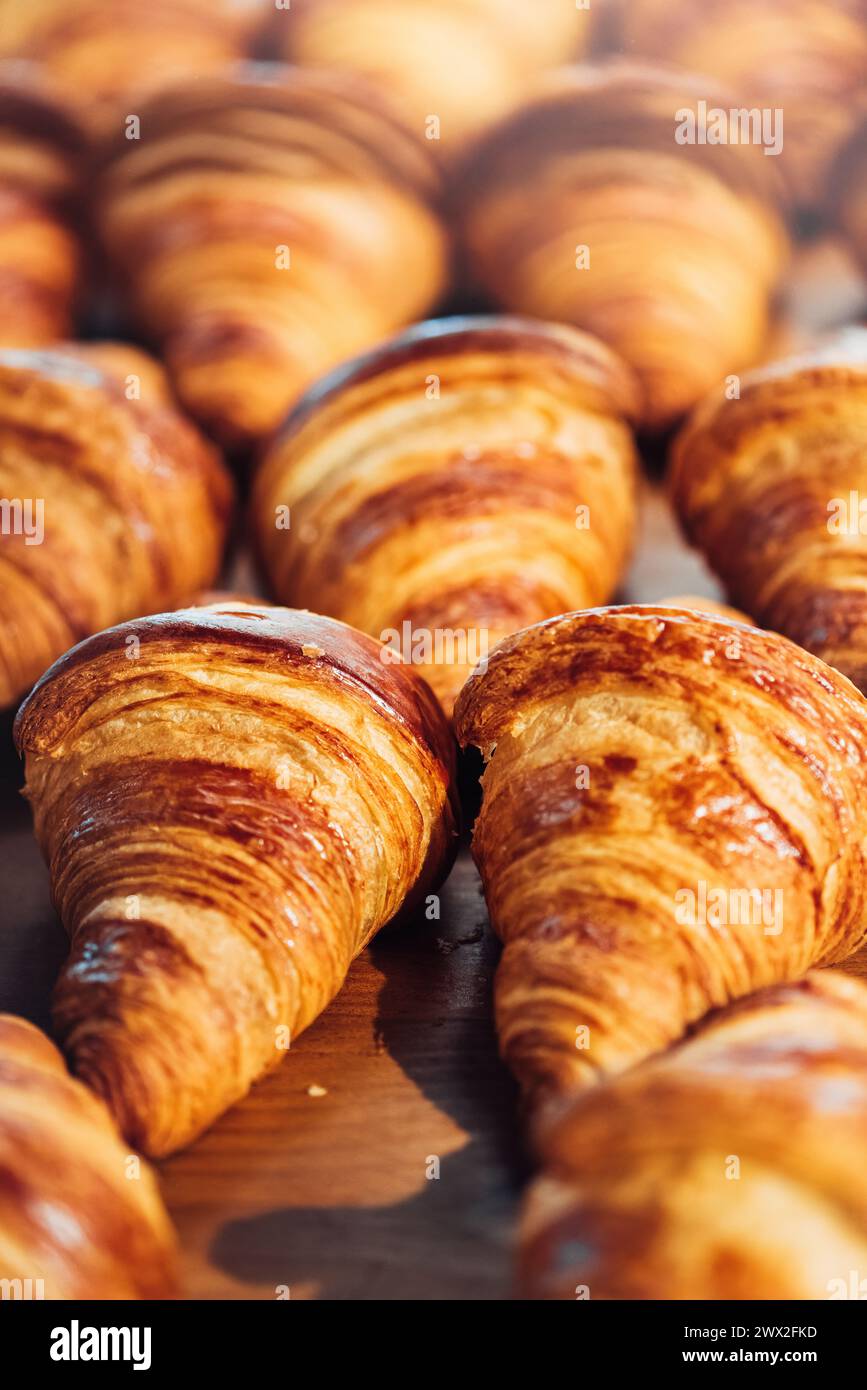 Una selezione di croissant dorati e' ordinatamente sistemata su una superficie di legno, che mostra la loro consistenza flaky e il colore ricco Foto Stock