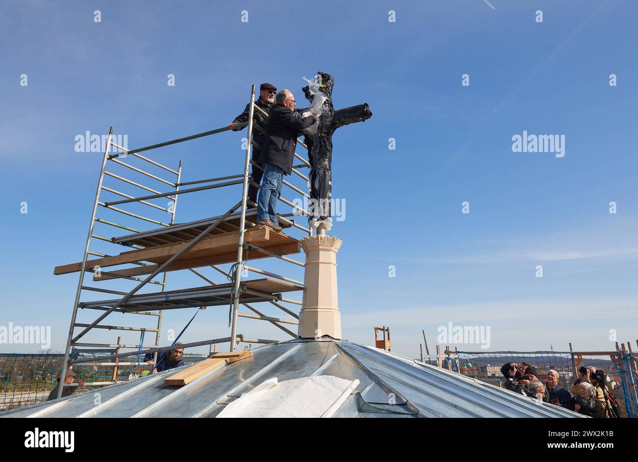 Nach fast zehn Jahren ist das Turmkreuz auf die evangelische Friedenskirche im Potsdamer Park Sanssouci zurueckgekehrt. DAS im November 2014 aus Sicherheitsgruenden abgenommene mehr als drei Meter hohe Kreuz wurde am Mittwoch 27.03.2024 wieder auf dem Campanile, dem Glockenturm der Kirche, enthuellt. Foto v.l.: Andreas Kitschke, Architekt und Denkmalpfleger Frank Karalus, Projektleitung, Abteilung Baudenkmalpflege und Liegenschaften, SPSG, enfernten gemeinsam die Schutzhuelle Der 1850 errichtete Turm wird seit February 2022 saniert. DAS Dach des rund 42 metri hohen Campanile sei inzwischen inst Foto Stock