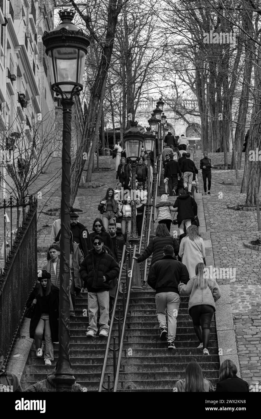 Parigi, Francia - 17 febbraio 2024: Veduta dei turisti che camminano su e giù per le pittoresche scale con le lanterne nell'area di Montmartre a Parigi Foto Stock