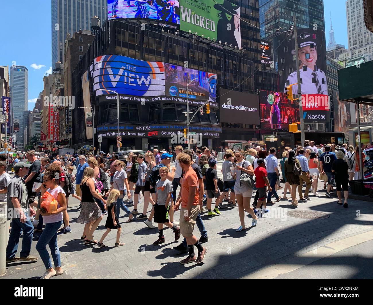 Durante la stagione estiva, grandi gruppi di turisti si mescolano con gli impiegati in una bella giornata di sole a Times Square a New York Foto Stock